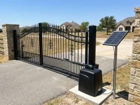 Entrance gates of a rural community, with a gate opener and a solar panel on a post