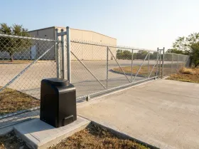 Chain-link slide gate and gate opener at the truck entrance of a warehouse