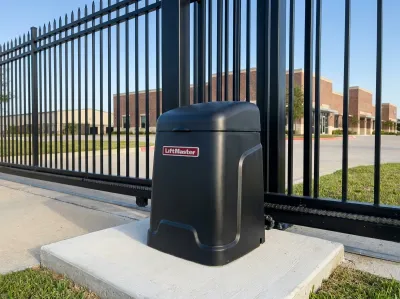 Black LiftMaster gate opener beside a steel slide gate at the entrance of a business park
