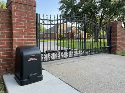 Black LiftMaster swing gate opener on a concrete pad, its arm attached to a wrought-iron driveway gate